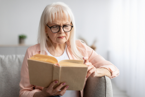 Senior man reading with difficulty due to blurry vision from cataracts