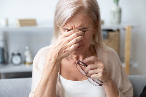 Woman frustrated with blurry tablet screen, motivating cataract procedure