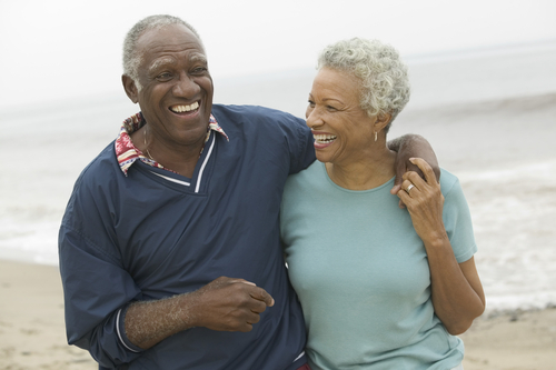 Joyful elderly African American couple embracing on sunny beach, celebrating active retirement with clear vision