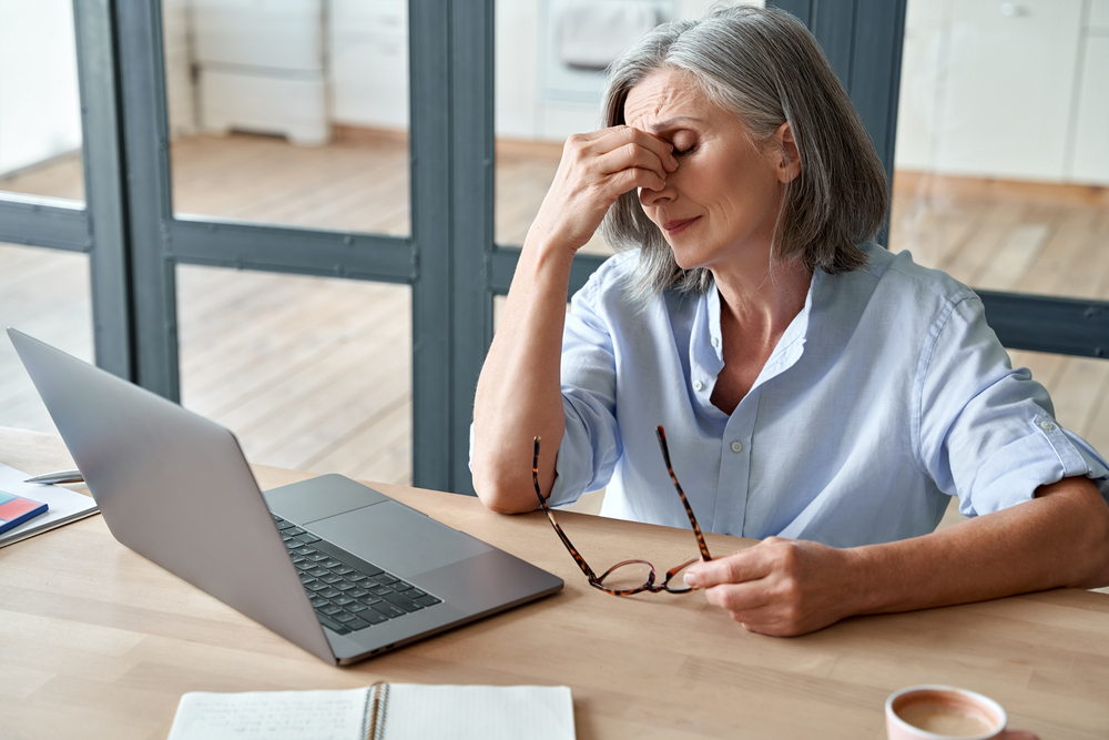 Elderly woman using tablet on couch, demonstrating clear digital vision after cataract treatment