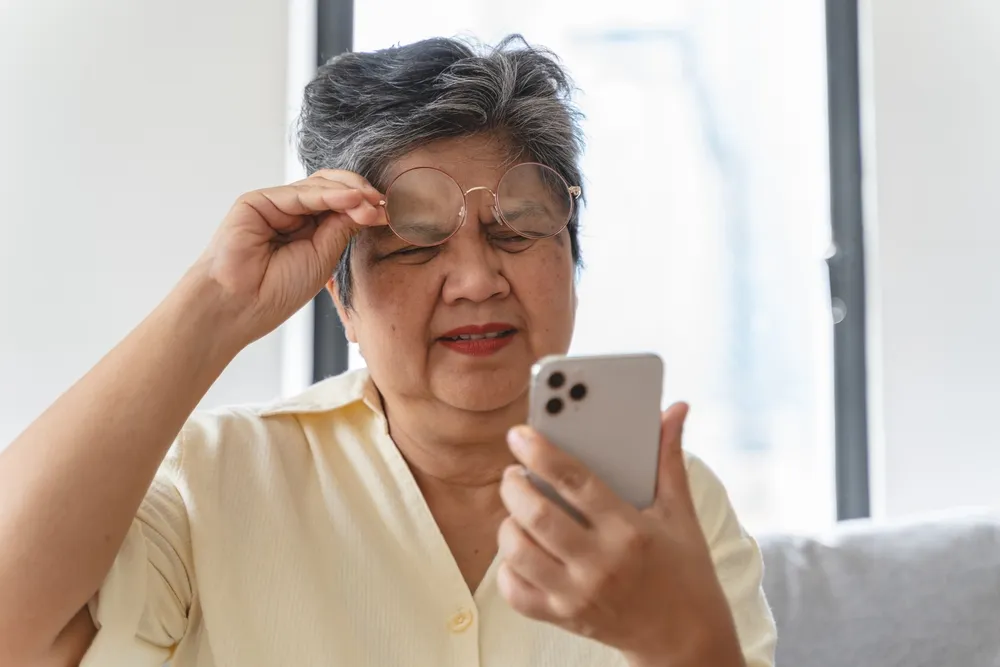Woman distressed on sofa with glasses, seeking relief from cataract symptoms