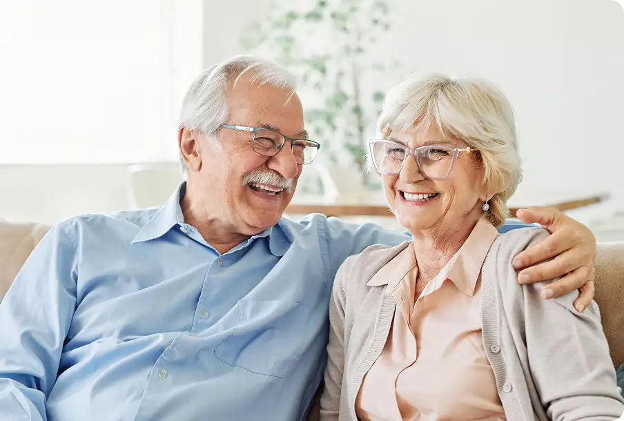 Elderly couple sipping coffee on sofa – intimate moments with sharp post-surgery vision.