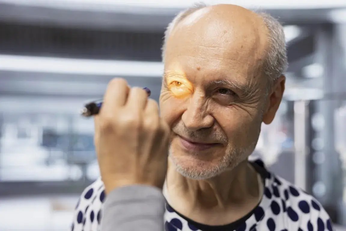 Ophthalmologist examining an adult patient’s eye with a handheld light.